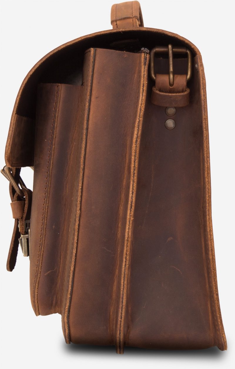 Side view of brown leather satchel with 2 compartments and 2 front asymmetric pockets.