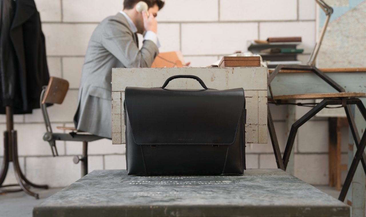 Man in office with the large black vegetable-tanned leather briefcase bag with laptop pocket.