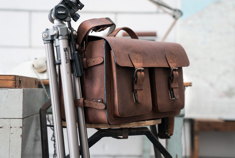 Large brown leather camera bag with tripod holder.